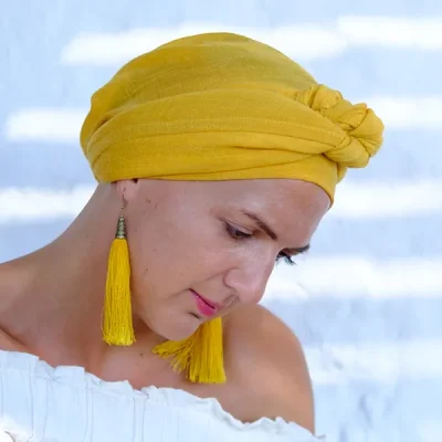 Beautiful woman with hair loss in yellow headscarf and earrings